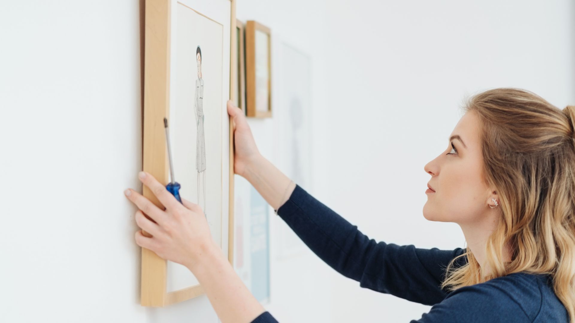 Woman hangs a picture on the wall