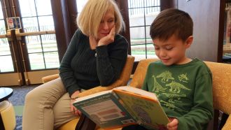 Child reads at Wright Library with adult.
